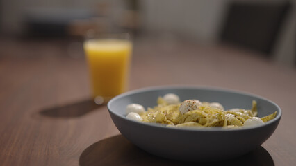 pesto fettuccine with mozzarella in blue bowl on walnut table