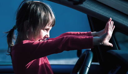 Dangers and risks of underage driving. A little child girl  panic in the car. Emergency, accident, hazard concept.