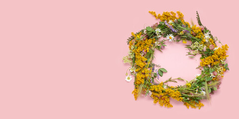 Beautiful wreath of wild flowers , typical Scandinavian midsummer decoration concept. Pink background. Top view. Copy space