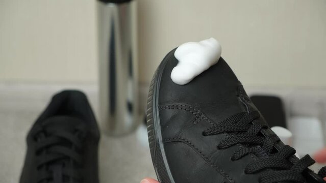 Applying cleaning foam from a bottle to nubuck men's shoes