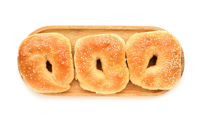 Wooden board of tasty bagels with sesame seeds on white background