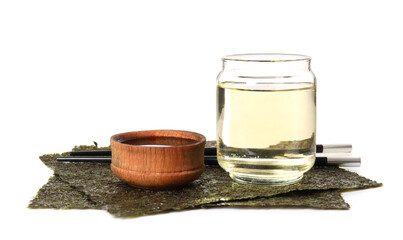 Glass of rice vinegar, soy sauce and nori sheets on white background