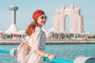 Fototapeta na wymiar Indian Girl walking along the Corniche promenade in Abu Dhabi, UAE, with its lush greenery and clean beaches, is a great way to unwind and soak up the sun while enjoying the fresh sea breeze.