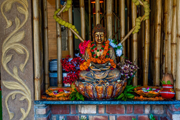 Obraz premium Bronze buddha statue sitting in meditation with flower decorations for festival ceremony. High quality photo