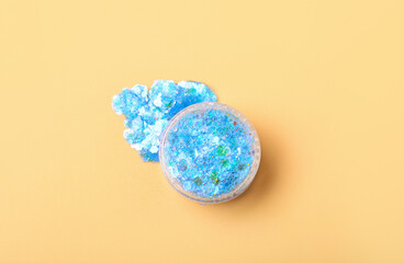 Jar of blue glitter on yellow background