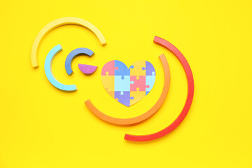 Paper heart with baby blocks on yellow background. World Autism Awareness Day