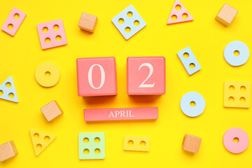 Date of World Autism Awareness Day with baby toys on yellow background