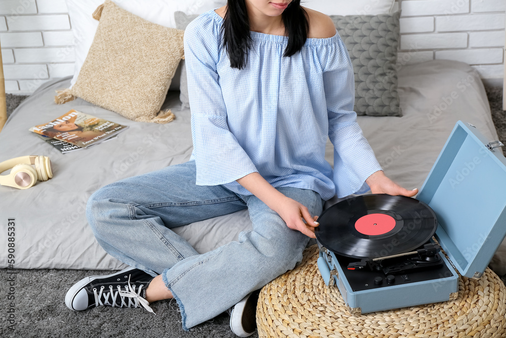 Wall mural Young woman with record player in bedroom