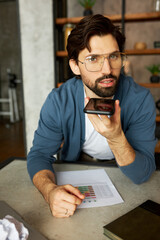Attractive photogenic intelligent man program developer sitting at working table at office using...