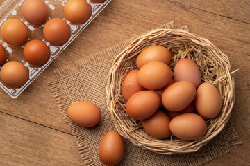 Heap of Chicken eggs on wicker basket on wooden plate background.Top view