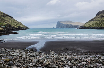 Beach in Tjornuvik, small charming fishing village in Streymoy, Faroe Islands, Northern Europe, view to Risin og Kellingin, big waves on the sea during the rainy day