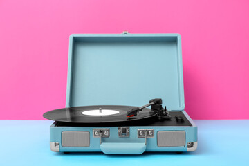 Record player with vinyl disk on table near pink wall © Pixel-Shot