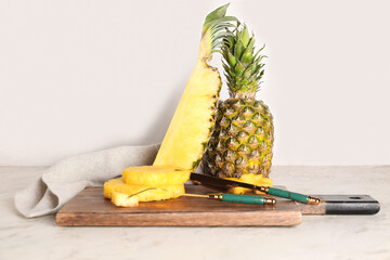 Wooden board with cut pineapple on light table