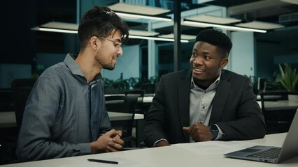 Two diverse men with laptop discuss project African american broker advisor manager consulting Indian man client satisfied businessmen shake hands partnership in office handshake at business meeting
