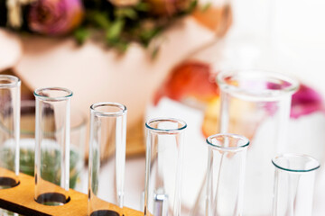 Fresh flowers in chemical test tubes on the table. Preparation of perfumes from natural ingredients, aromatherapy