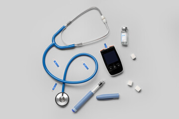 Glucometer with sugar, insulin and stethoscope on grey background. Diabetes concept