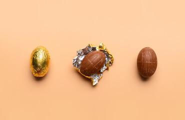 Obraz premium Chocolate Easter eggs in golden foil on beige background