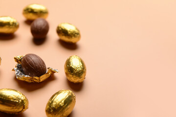 Chocolate Easter eggs in golden foil on beige background