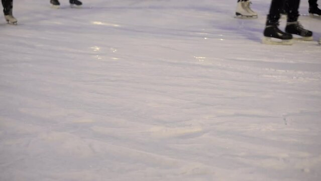 Unrecognizable people ice skate on the rink. Legs of people in skates.