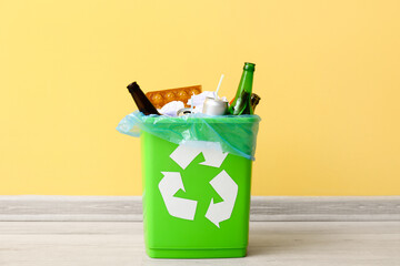 Recycling bin with garbage near yellow wall