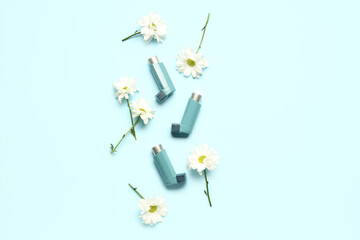 Asthma inhalers with daisy flowers on blue background