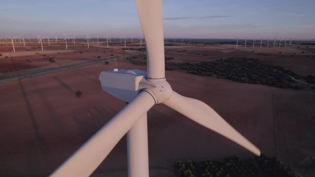 Aerial Close-Up View of a Wind turbine with a group (group of objects) of Wind turbines (farm) turning and producing electricity natural energy at sunset, Renewable Energy, Wind Energy, Cuenca, Spain