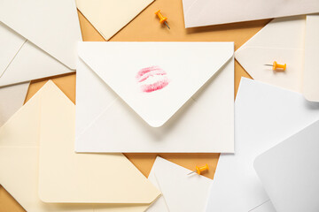Envelopes with lipstick kiss mark on orange background