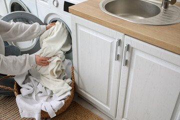 Fototapeta na wymiar Woman putting dirty clothes in washing machine at home, closeup