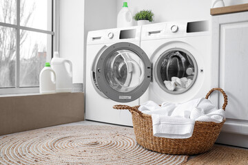 Modern washing machines with dirty clothes in laundry room