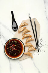 Tasty Chinese jiaozi, sauce and sesame on light background