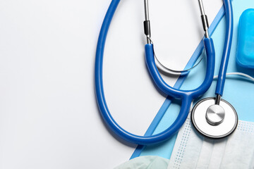 Stethoscope, clipboard and medical mask on blue background, closeup