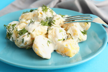 Plate of tasty Potato Salad with greens on blue background, closeup
