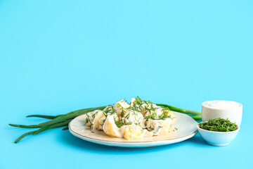 Plate of tasty Potato Salad with greens on blue background