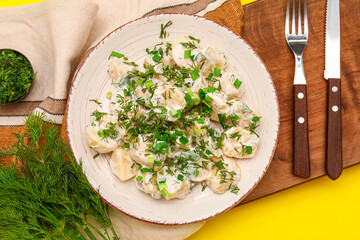 Plate of tasty Potato Salad with greens on yellow background