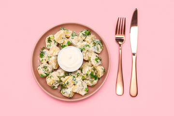 Plate of tasty Potato Salad with greens on pink background