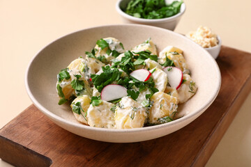 Plate of tasty Potato Salad with greens on yellow background, closeup