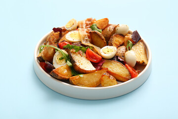 Plate of tasty potato salad with eggs, tomatoes and bacon on light blue background