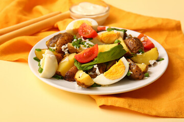 Plate of tasty potato salad with eggs and tomatoes on beige background