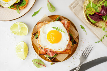 Delicious sandwich with fried egg and bacon on light background