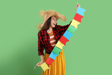 Young woman with flags on green background. Festa Junina (June Festival) celebration