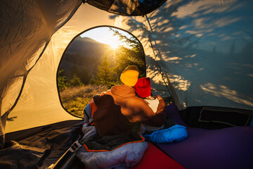 Family vacation lifestyle. Children rest in tourist tent looking at the mountain landscape at sunset.