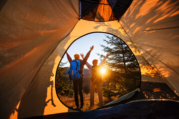 Family camping in the mountains. Children tourists stand with their hands raised to the sun. View...