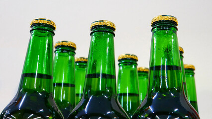 Close-up of many beautiful green glass bottles of beer with golden caps on a store shelf