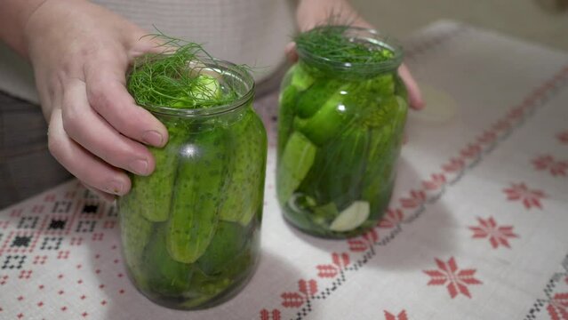 pickled cucumbers in glass jars,a woman closes pickled cucumbers with a lid, preparing cucumbers for the winter