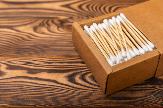 Cotton swabs in a craft box on a brown textured wood. Bamboo cotton buds. Means for hygiene of ears. Eco-friendly materials.Hygienic cotton ear buds.
