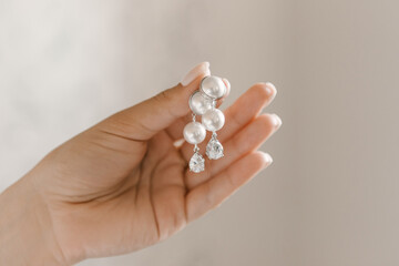 Fototapeta na wymiar Beautiful white pearl earrings in women's hands
