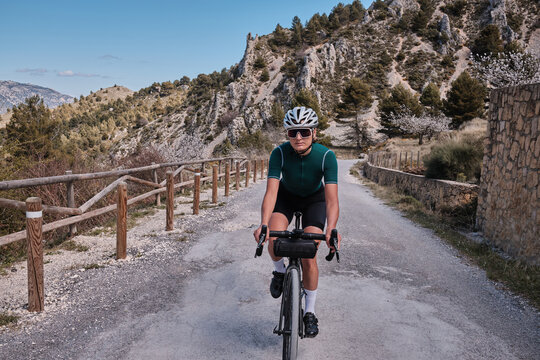 Spanish gravel adventures.Female cyclist riding a gravel bike on a gravel road with a view of the mountains.Beautiful sunny day for cycling.Beautiful motivation image of an athlete.Spain.