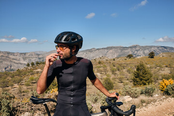 Cyclist is resting.Male cyclist is wearing cycling kit holding energy snack for endurance during...