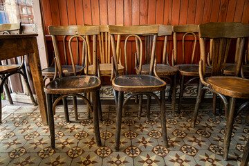 Selective focus on antique brown wooden chairs with vintage style in front of red brown wooden wall...