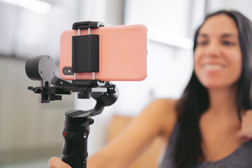 Close-up of a smartphone held by a gimbal while being used by a blurred woman holding it.